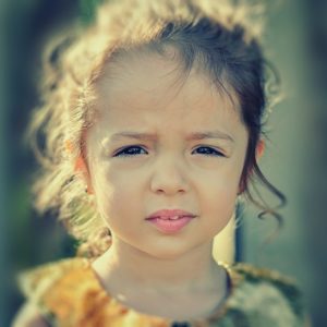 Foto av en ung jente på 6-7 år med brune øyne og brunt hår som ser inn i kamera.
