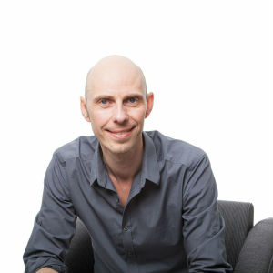 Mann ser inn i kameraet og smiler.